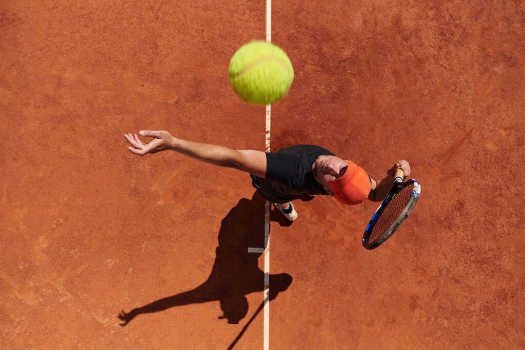 BB Capital - Top view of a professional tennis player serves the tennis ball on the court with precision and power